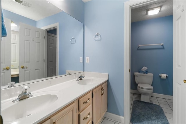 bathroom featuring tile patterned floors, vanity, toilet, and a textured ceiling