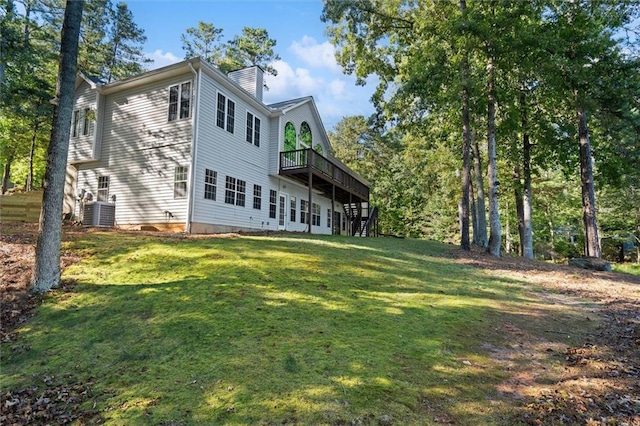 rear view of property featuring central AC unit, a wooden deck, and a lawn