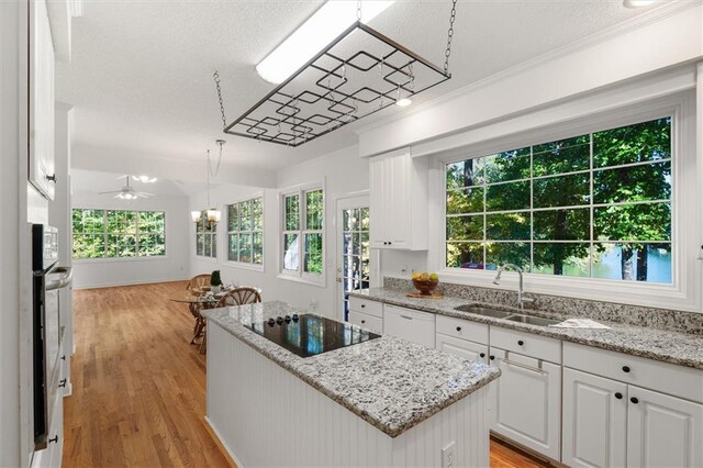 kitchen with a center island, black electric cooktop, white cabinetry, and light hardwood / wood-style floors