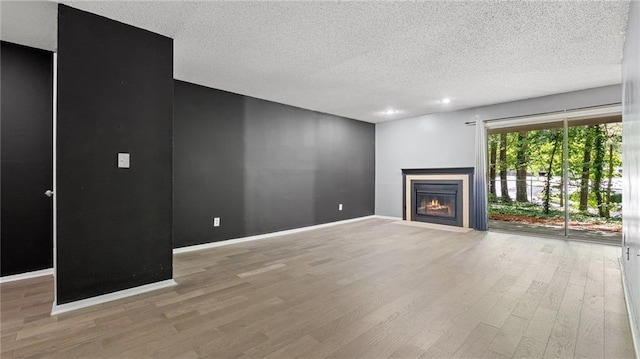 47 Arbor End, Smyrna, GA 30080 - unfurnished living room featuring wood finished floors, a fireplace with flush hearth, and a textured ceiling