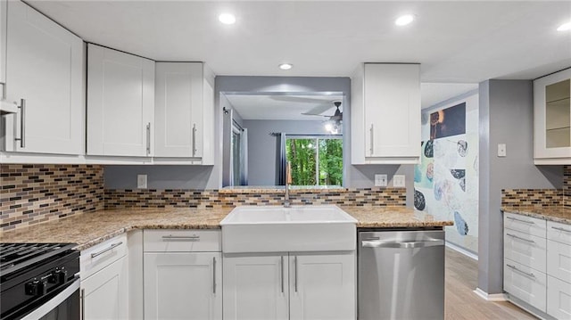 47 Arbor End, Smyrna, GA 30080 - kitchen featuring stainless steel dishwasher, gas range oven, light wood-style floors, white cabinets, and backsplash