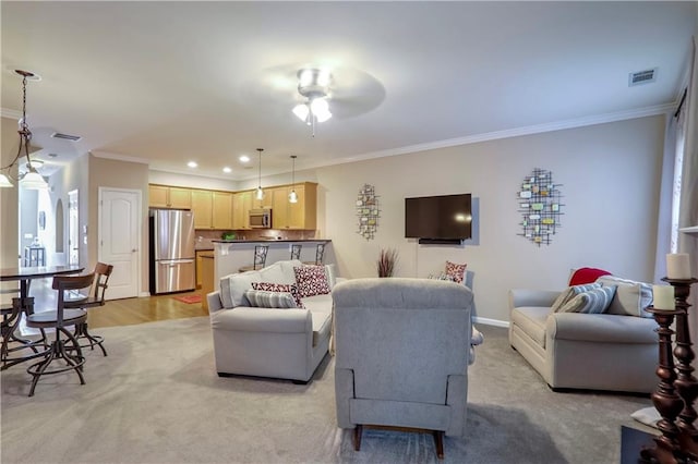 living room with ceiling fan, light colored carpet, and ornamental molding