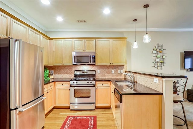 kitchen with kitchen peninsula, appliances with stainless steel finishes, a kitchen breakfast bar, sink, and pendant lighting