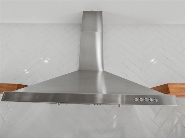 kitchen featuring wall chimney exhaust hood, stainless steel gas range, and tile walls