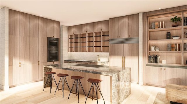 kitchen with a breakfast bar, double oven, dark stone counters, and sink