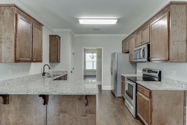 63 Emma Ln, Winder, GA 30680 - kitchen with appliances with stainless steel finishes, a sink, dark wood-type flooring, a breakfast bar area, and a peninsula