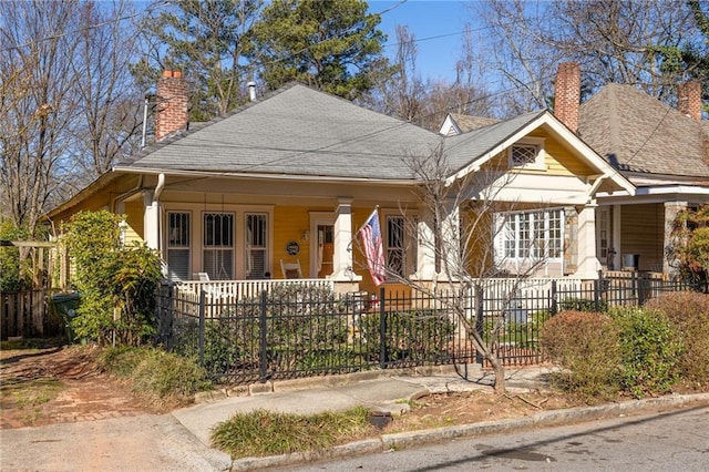 view of front of property with a porch, a fenced front yard, and a chimney