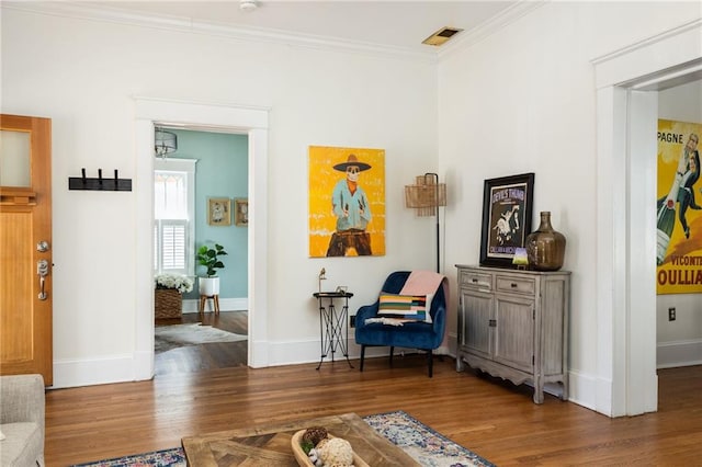 living area featuring baseboards, wood finished floors, and crown molding