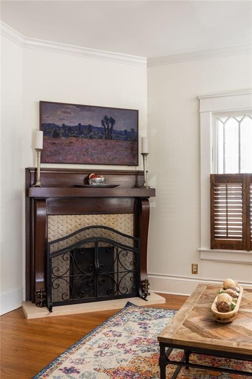 interior space featuring baseboards, a fireplace, ornamental molding, and wood finished floors