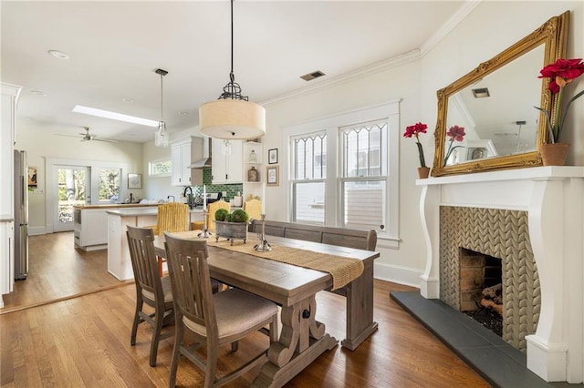 dining room featuring a fireplace, wood finished floors, visible vents, and crown molding