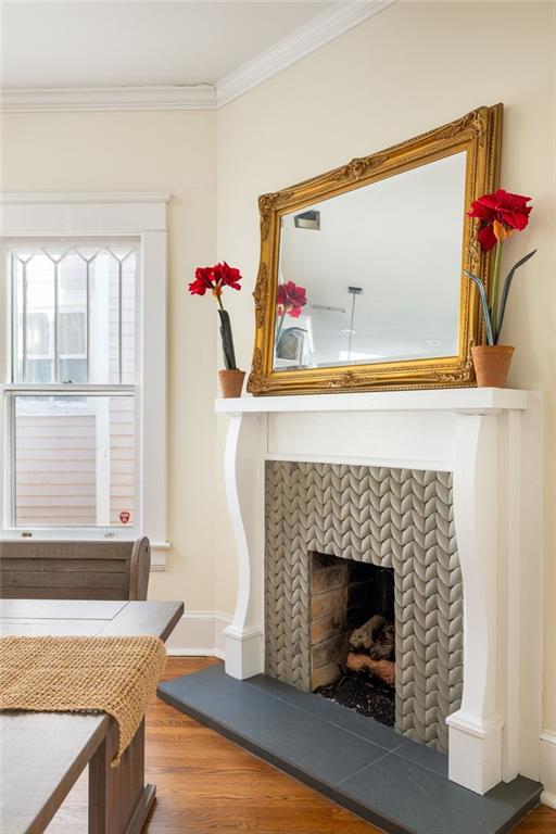 interior details with baseboards, a fireplace, wood finished floors, and crown molding