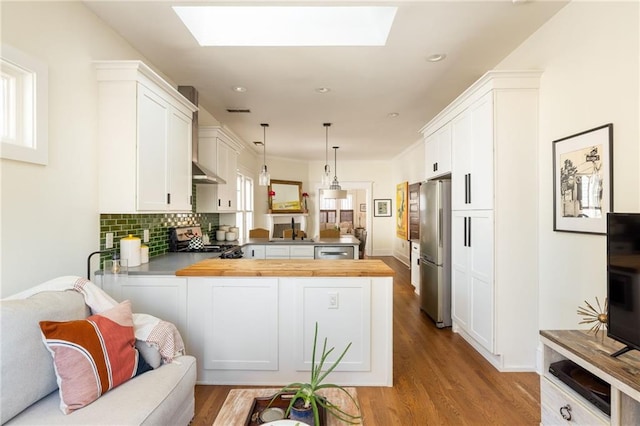 kitchen featuring a peninsula, appliances with stainless steel finishes, a skylight, and white cabinets