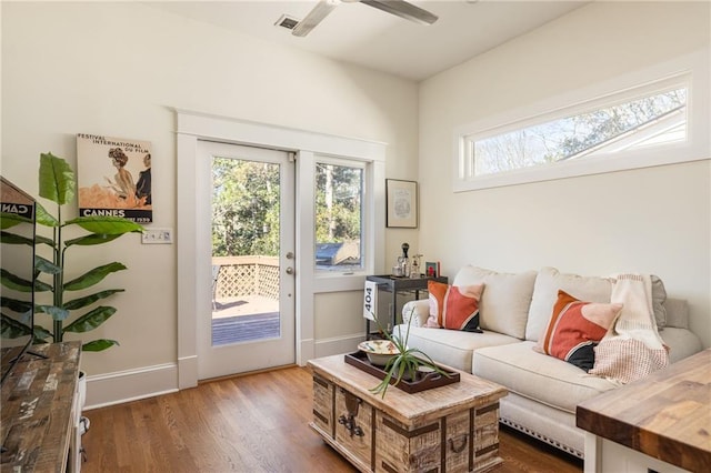 living area featuring visible vents, ceiling fan, baseboards, and wood finished floors