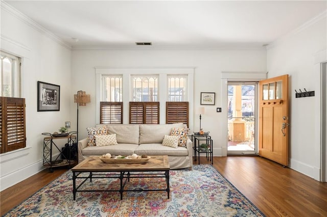 living area featuring baseboards, visible vents, wood finished floors, and ornamental molding