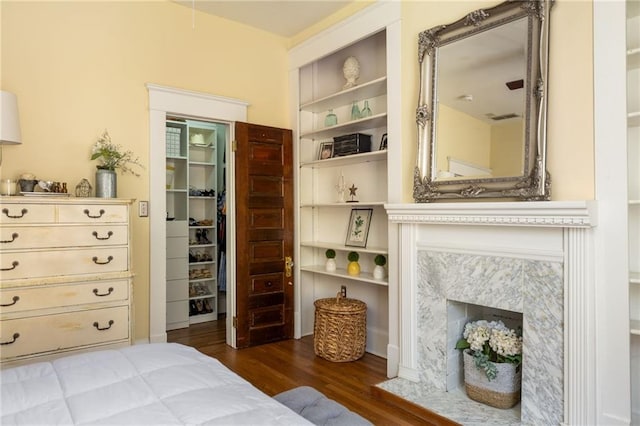 bedroom featuring a closet, a spacious closet, a premium fireplace, and wood finished floors