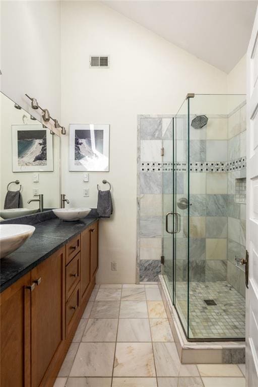 bathroom with lofted ceiling, a sink, visible vents, double vanity, and a stall shower