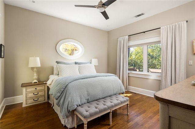 bedroom featuring dark wood-type flooring, a ceiling fan, visible vents, and baseboards