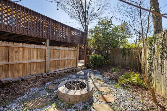 view of yard with a fire pit, fence, and a wooden deck