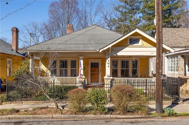 bungalow with a chimney, fence, a porch, and roof with shingles