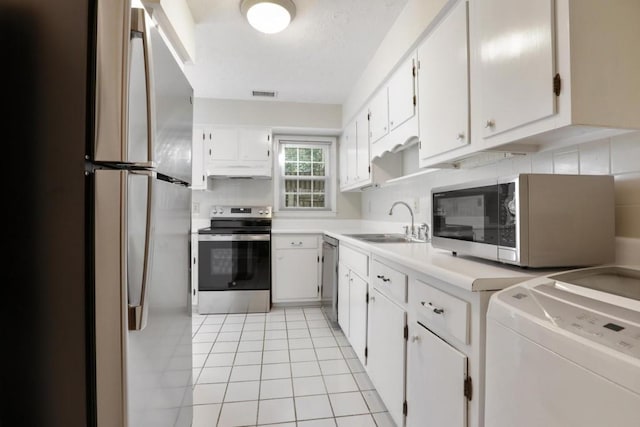 kitchen with a sink, washer / dryer, light countertops, appliances with stainless steel finishes, and visible vents