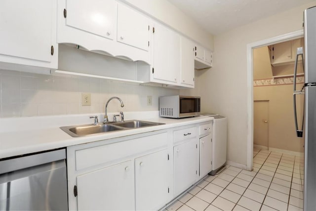 kitchen featuring a sink, light tile patterned flooring, stainless steel appliances, light countertops, and white cabinets