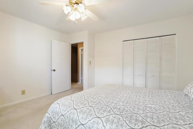 bedroom with light carpet, a ceiling fan, baseboards, and a closet