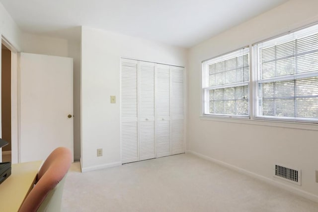 unfurnished office featuring baseboards, visible vents, and light colored carpet