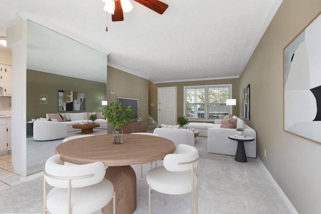 dining room with crown molding, baseboards, a ceiling fan, and light colored carpet