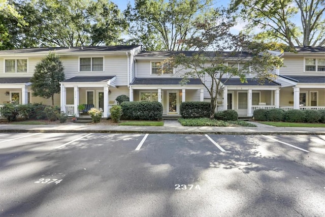 view of property with covered porch and uncovered parking