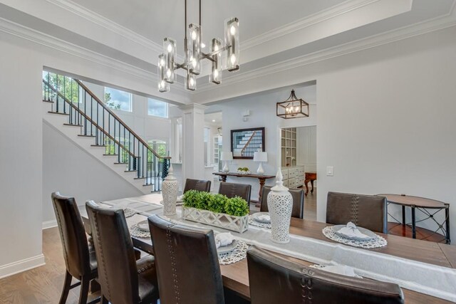 dining space featuring ornamental molding, hardwood / wood-style floors, ornate columns, and a notable chandelier