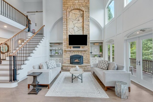 living room with a high ceiling, hardwood / wood-style floors, a fireplace, and a healthy amount of sunlight