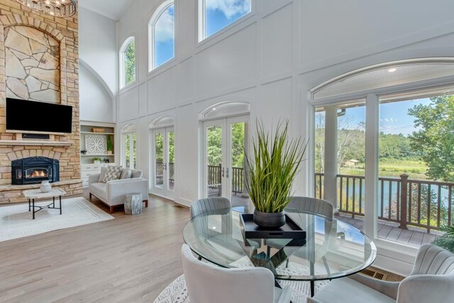 interior space featuring a towering ceiling, a stone fireplace, and wood-type flooring