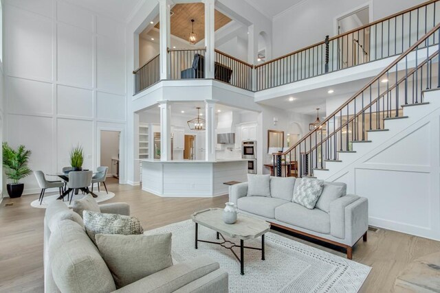 living room featuring a high ceiling, light hardwood / wood-style floors, and ornamental molding