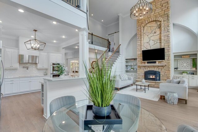 interior space with a fireplace, ornamental molding, light hardwood / wood-style flooring, and an inviting chandelier