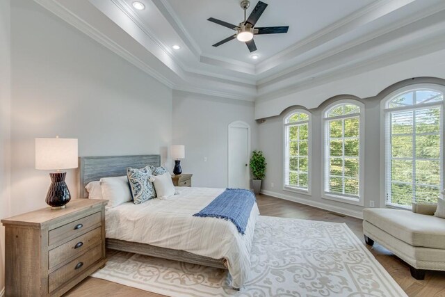 bedroom with ornamental molding, a tray ceiling, ceiling fan, and light hardwood / wood-style floors