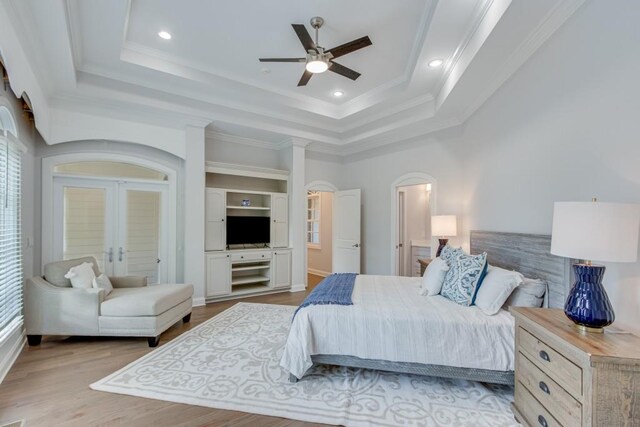 bedroom featuring crown molding, light hardwood / wood-style flooring, ceiling fan, and a raised ceiling