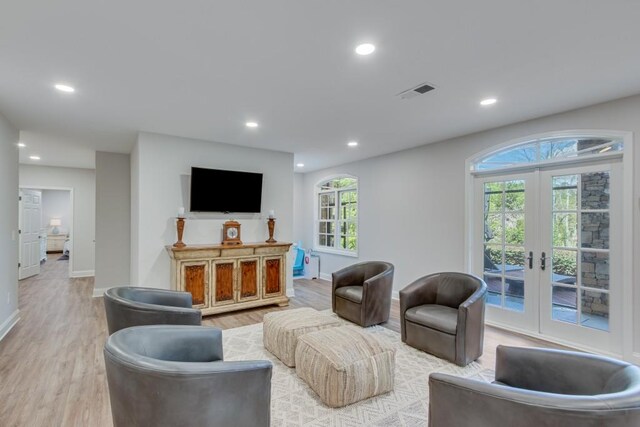 living room featuring french doors, a wealth of natural light, and light hardwood / wood-style flooring