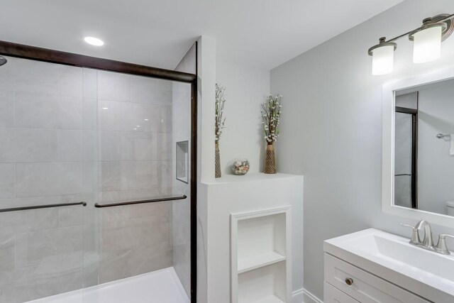 bathroom with toilet, a shower with door, and vanity