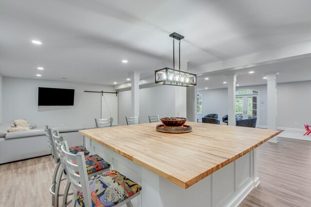 interior space with hanging light fixtures, a center island, french doors, a barn door, and light hardwood / wood-style floors