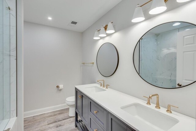 bathroom featuring hardwood / wood-style floors, walk in shower, toilet, and vanity