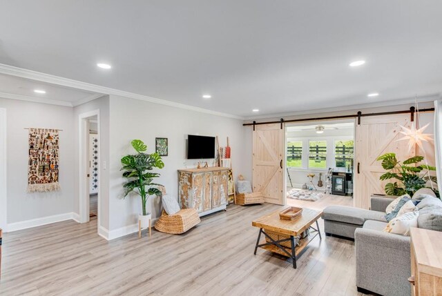 living room with a barn door, ornamental molding, and light hardwood / wood-style flooring