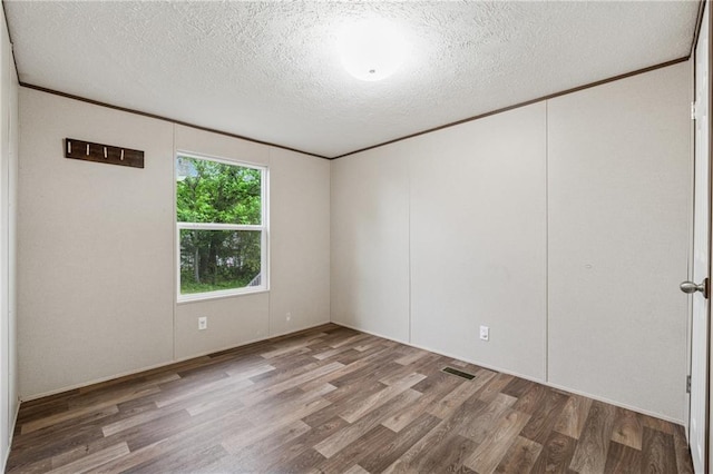 spare room with visible vents, wood finished floors, and a textured ceiling
