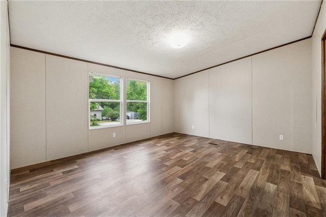 unfurnished room featuring a decorative wall, wood finished floors, and a textured ceiling