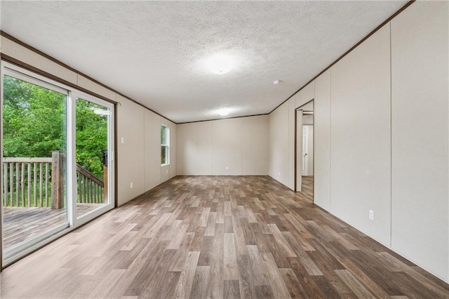 unfurnished room featuring wood finished floors, a textured ceiling, and a decorative wall