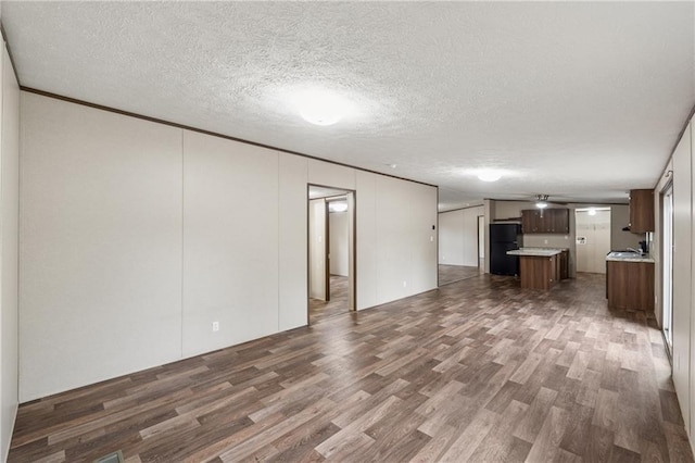 unfurnished living room with a textured ceiling, a sink, and dark wood-type flooring