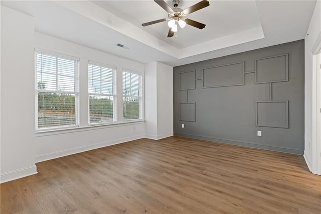 unfurnished room with ceiling fan, wood-type flooring, and a tray ceiling