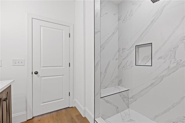 bathroom featuring hardwood / wood-style floors, vanity, and a tile shower