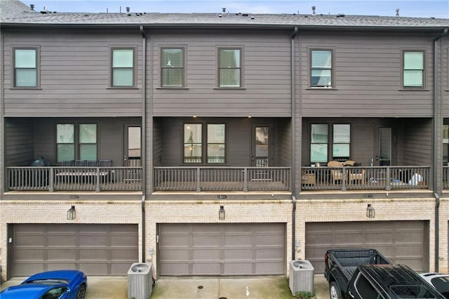 back of property with a garage, a balcony, and central air condition unit