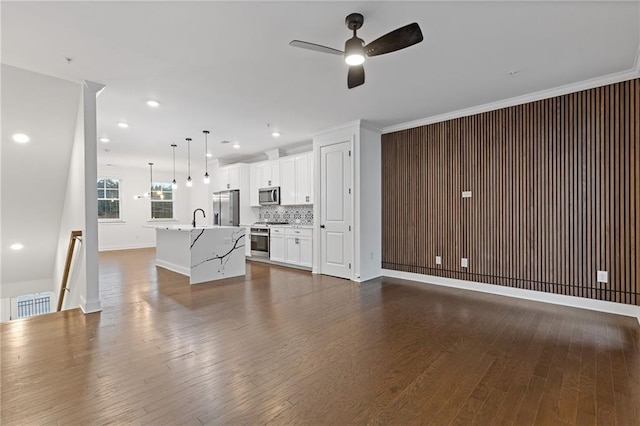 unfurnished living room with ceiling fan, sink, dark hardwood / wood-style floors, and crown molding