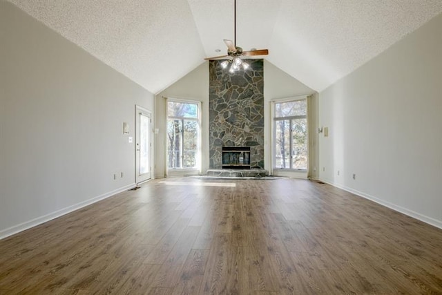 unfurnished living room with dark wood-type flooring, ceiling fan, a fireplace, and a textured ceiling